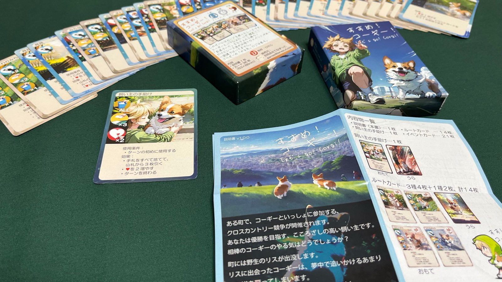すすめ!コーギー!の箱、ルートカード、イベントカード、説明書を卓上に広げた様子